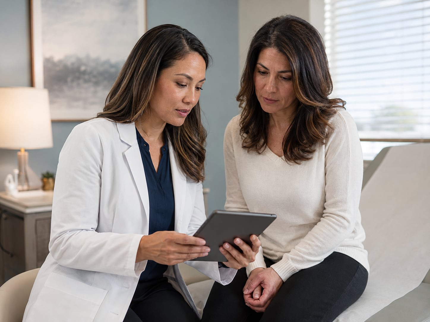 Two female clinicians review information together on a tablet