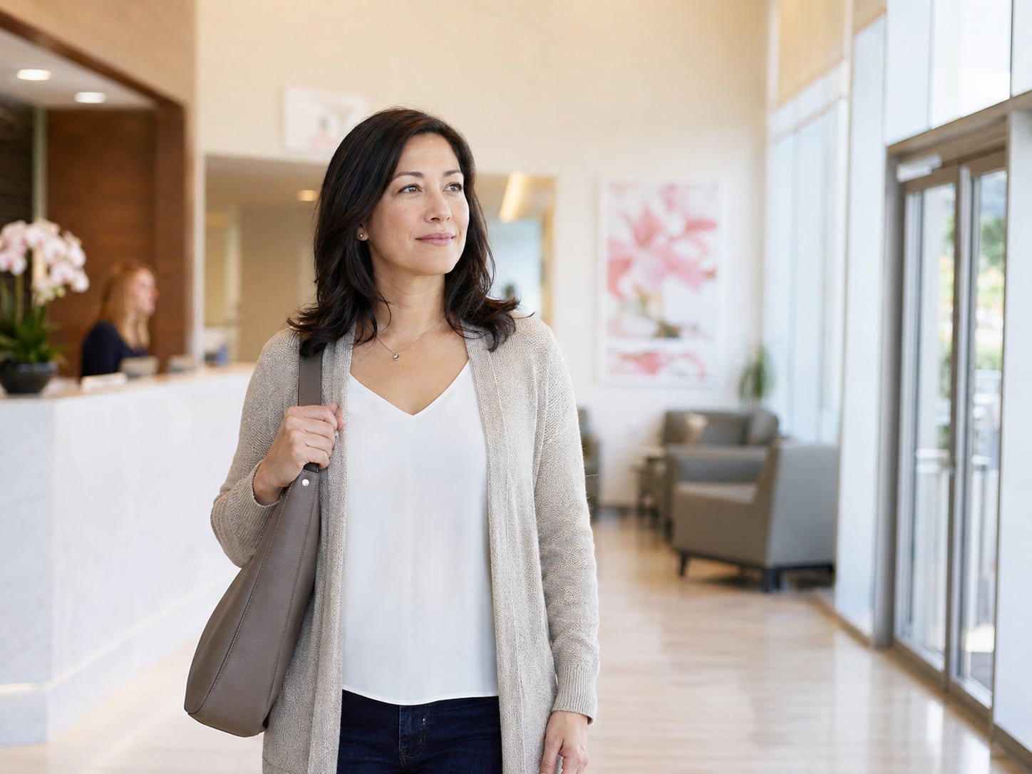 A woman walks through a bright clinic lobby carrying a bag