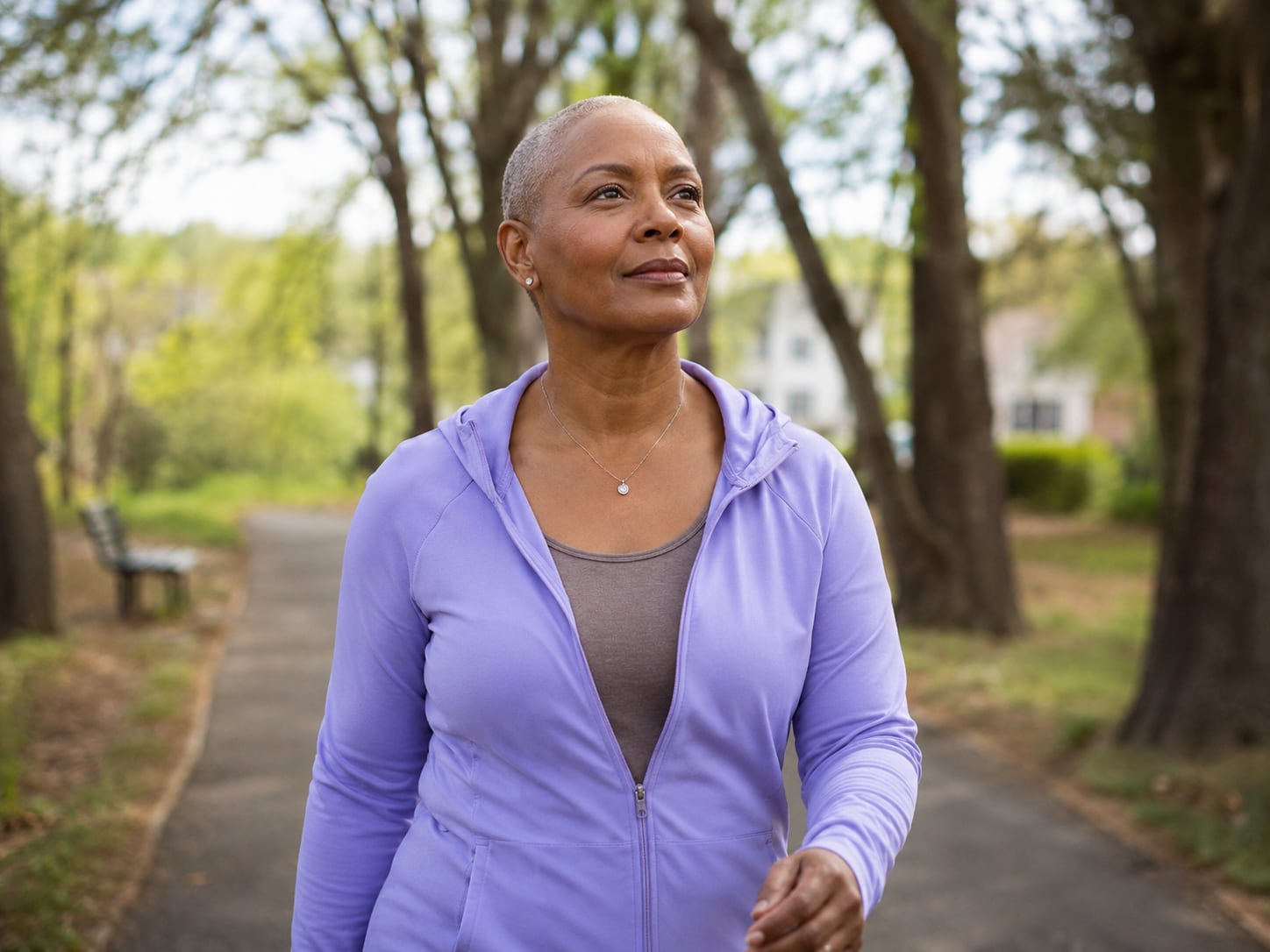 A woman in a purple hoodie walks alone on a park path