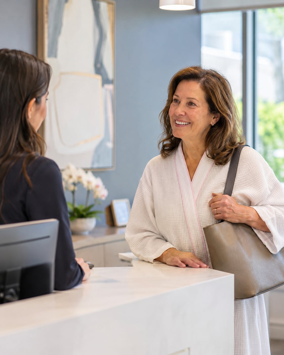 Two women smile at each other in close conversation indoors