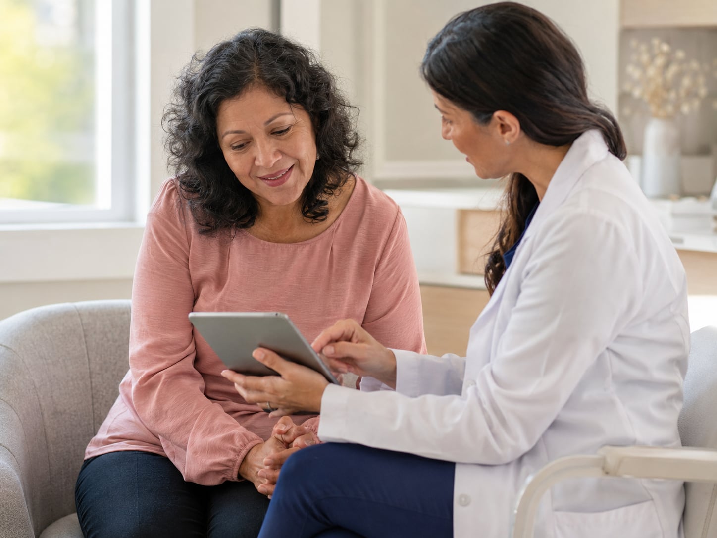 A doctor shows a tablet screen to a smiling woman patient
